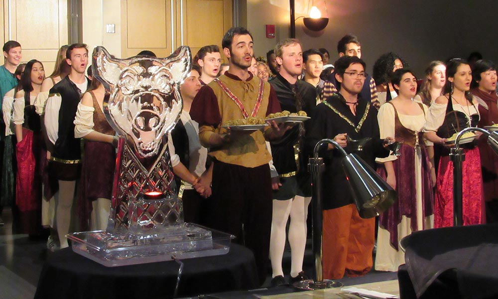 singers in costume carrying food at Boar's Head Dinner