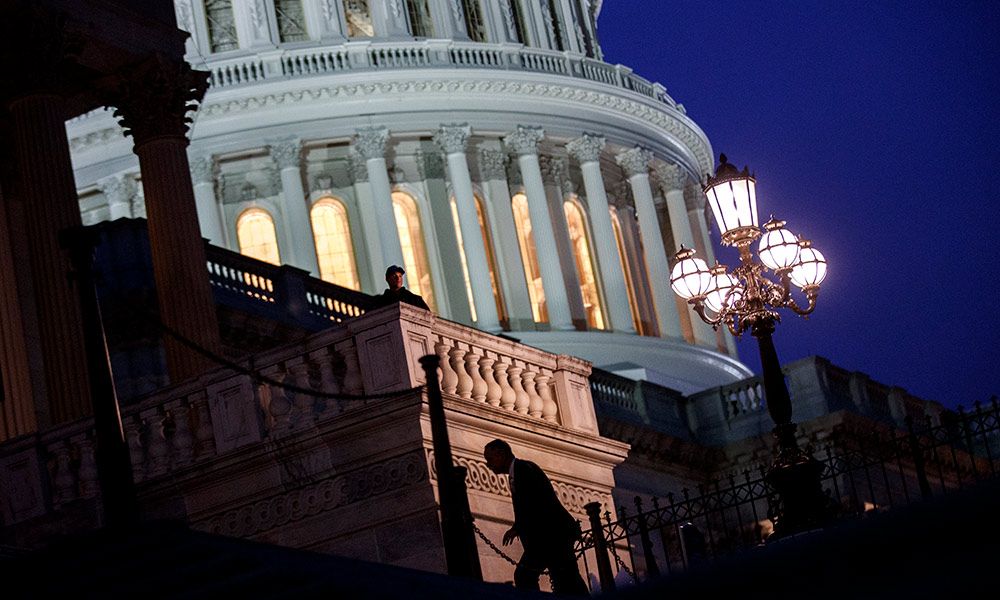 Feature image the Capitol building at night, with a single person running up the stair