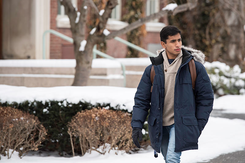 young man walking through a snowy quad