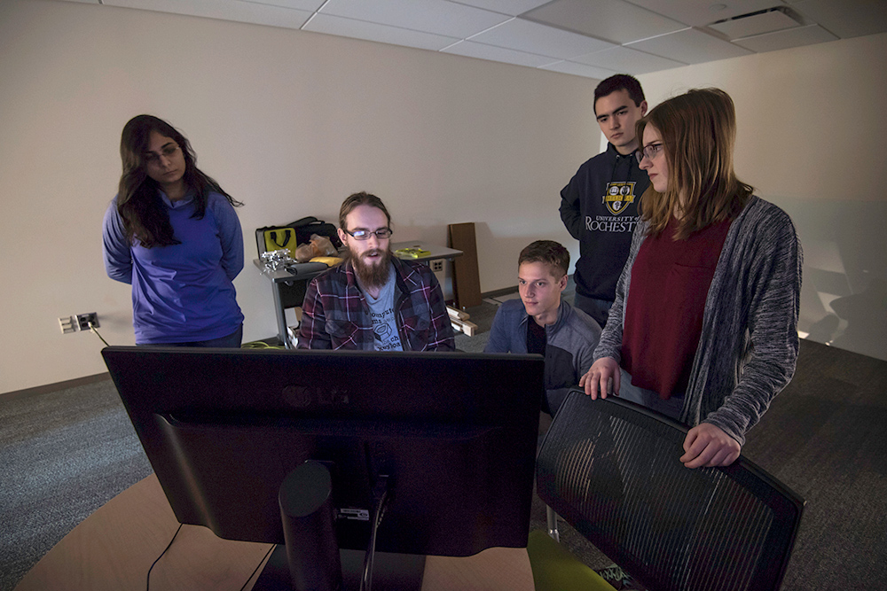 group of students standing around a computer display