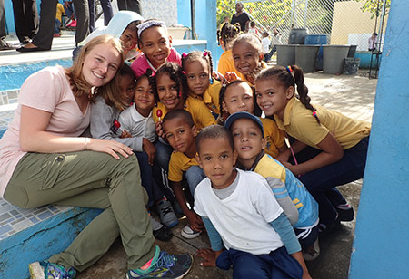 student poses with large group of children