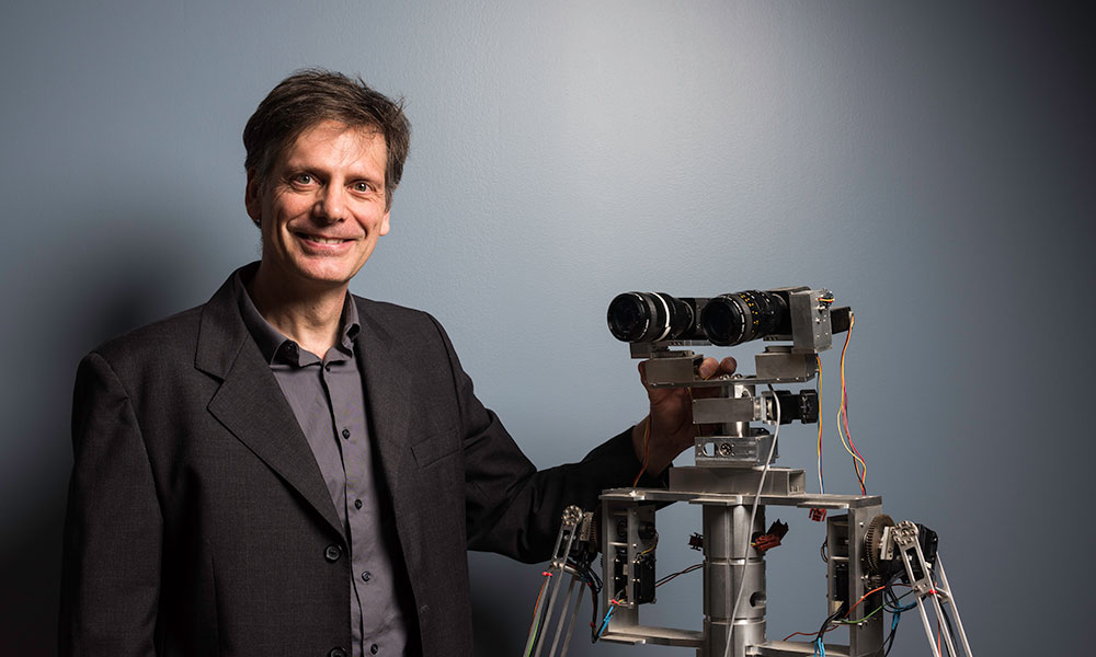 Michele Rucci poses with a robot with two large eyes