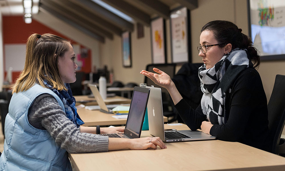 Feature image two people speaking at a desk, one receiving career advice from the other