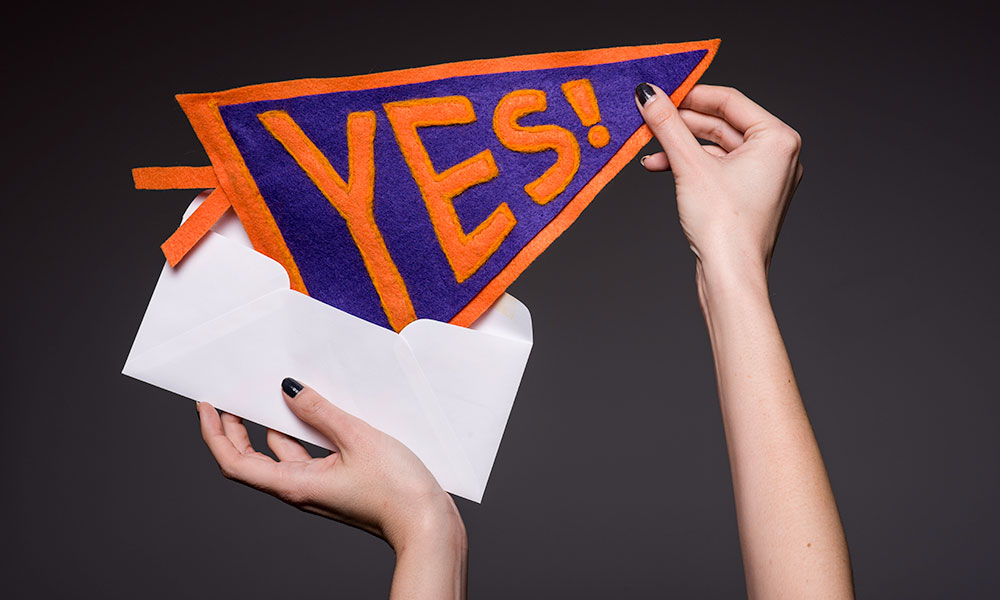 get into your dream college two hands pulling pennant out of an envelope. The pennant reads YES!