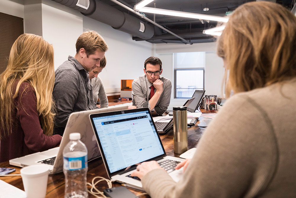 people sitting around a table and a laptop in the fabrication lab in the new NextCorp business incubator