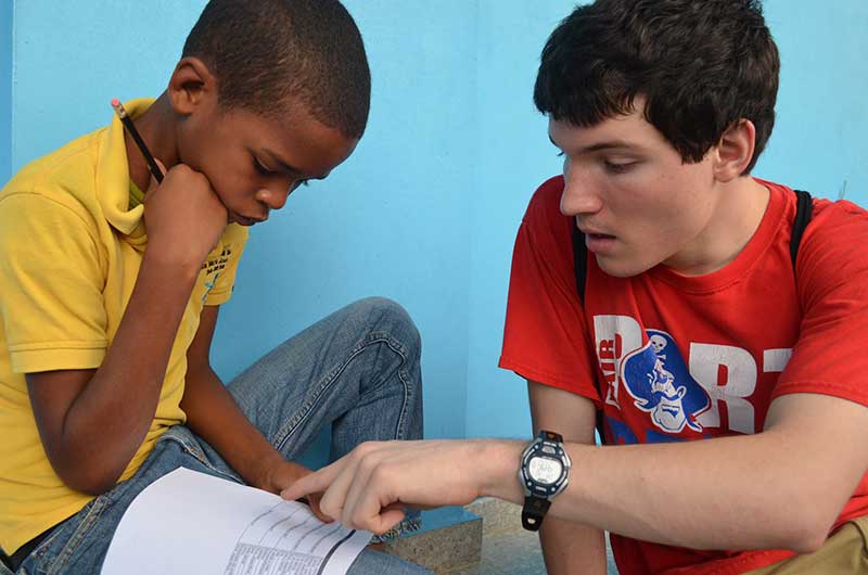 University student works together, reading a survey with a child