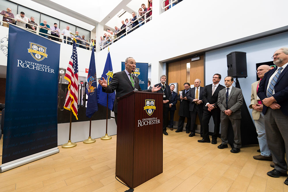 Feature image Senator Chuck Schumer standing behind a podium in front of a large group of people