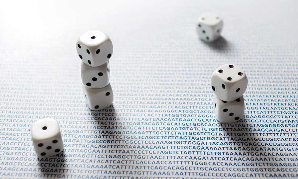 a pile of dice sitting a table covered in the A T C G letters of DNA