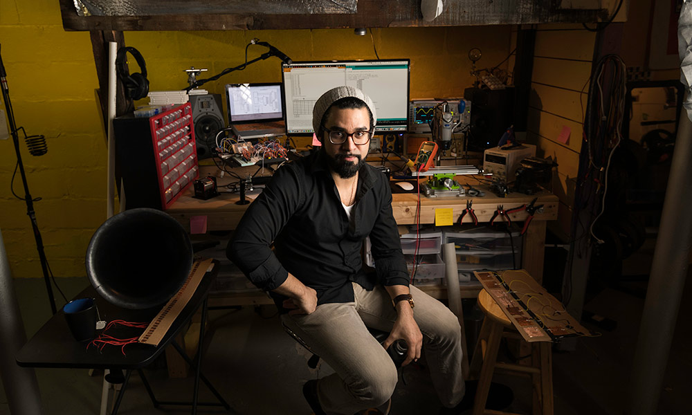 student surrounded by electronic equipment in his workshop / lab