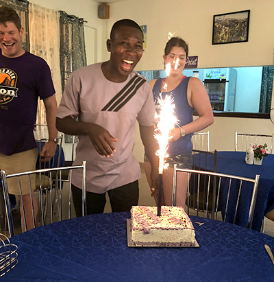 candle on a birthday cake shoots sparks into the air as man smiles and laughs