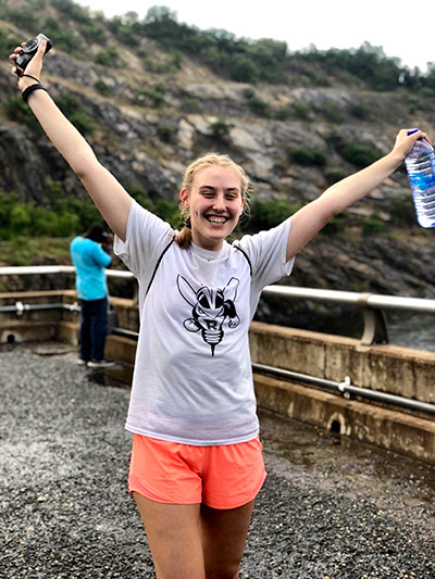 student in a Rocky t-shirt raises hers arms and cheers