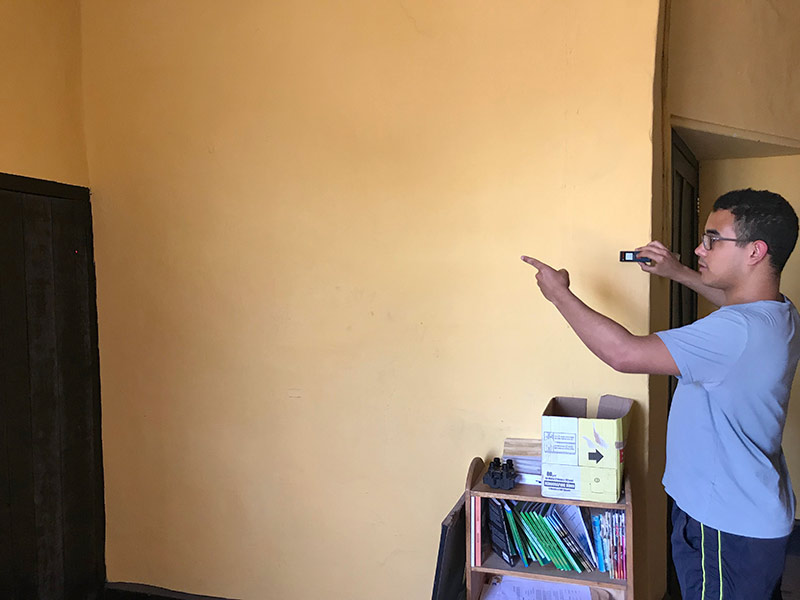 student holding an measuring instrument against a wall