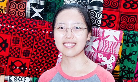 woman posing and smiling in front of colorful textiles