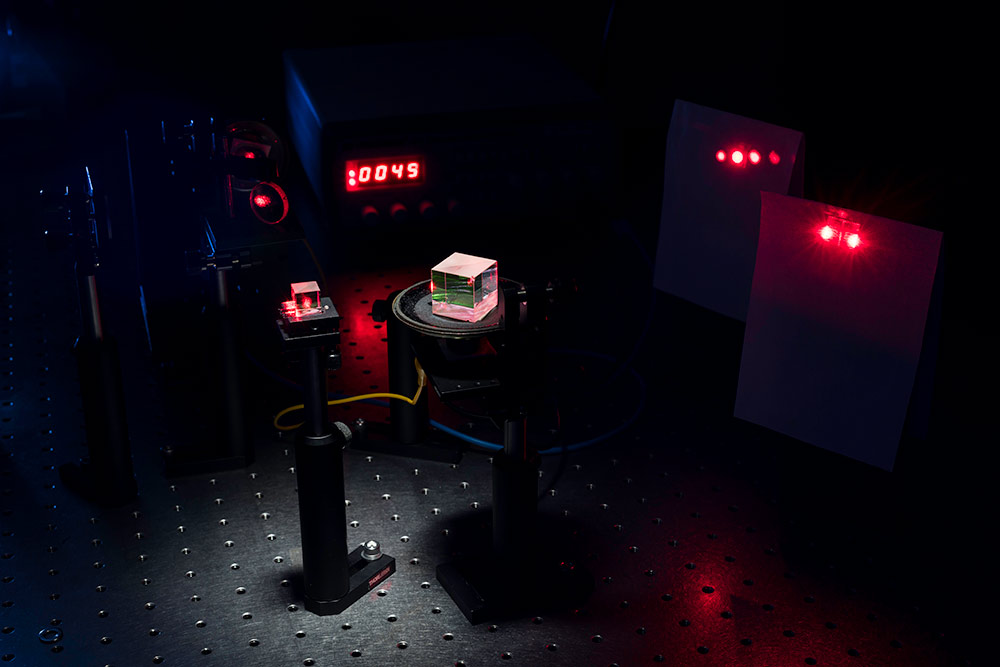 two small cubes with beams of light projecting through them and a digital clock display in the background