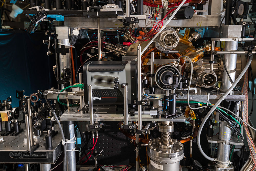 lab with a vacuum chamber amid a collection of wires, mirrors, and lenses