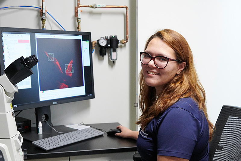 students in front of a computer screen smiles for a portrait