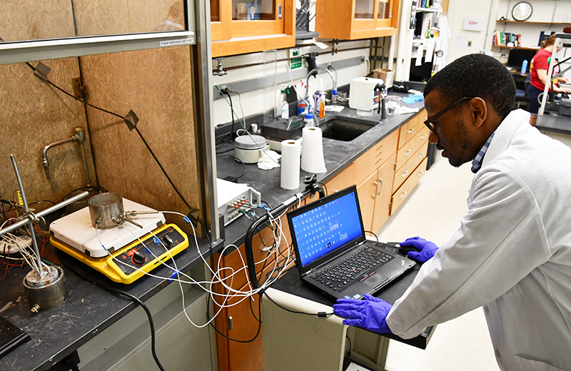 student wearing a lab coat using a compture connected to a device