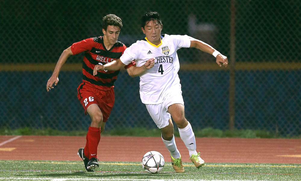 varsity sports soccer players chase a ball
