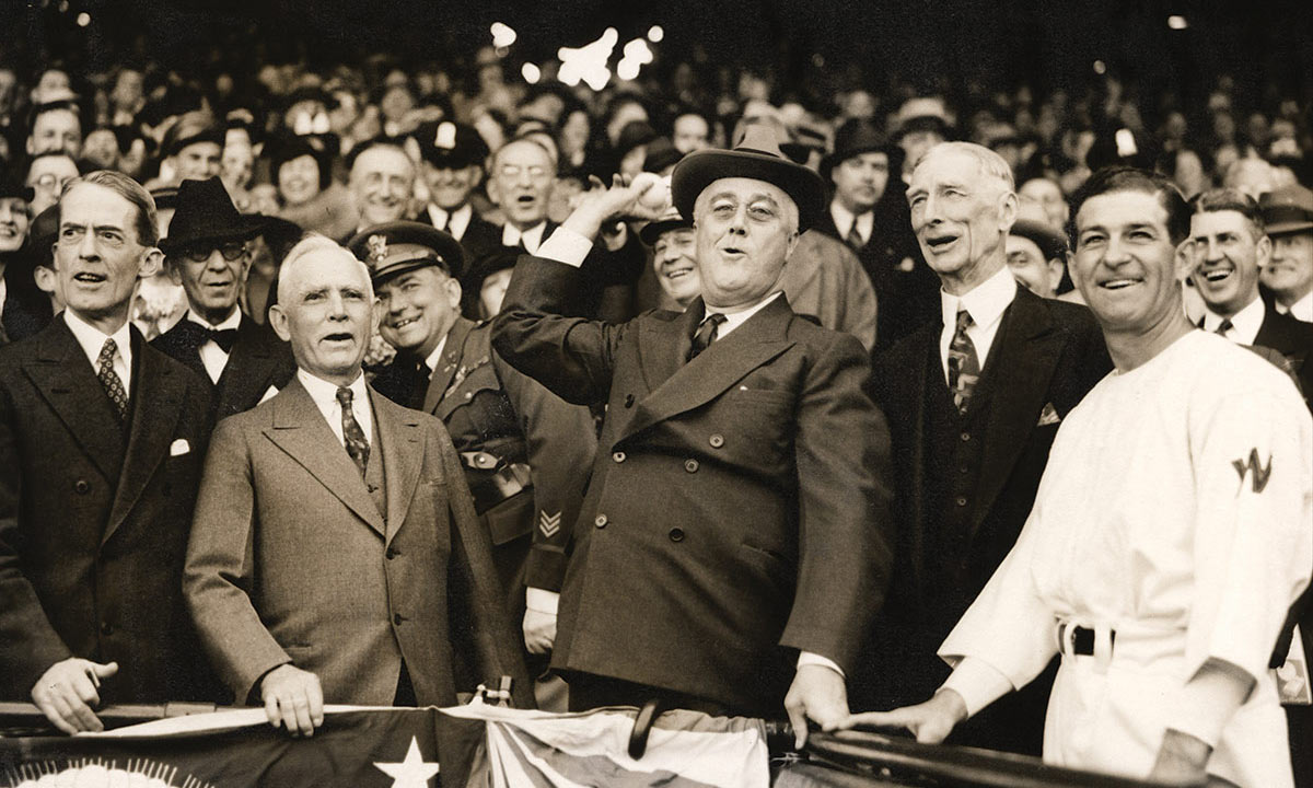 archival photo of FDR throwing out a pitch from the stands at a baseball game.