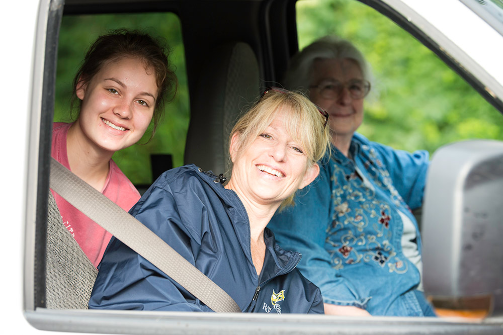 family of three poses for a photo from inside their car