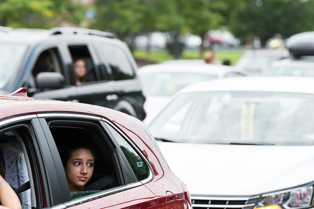 student with a pensive look stares out the window of her parked car