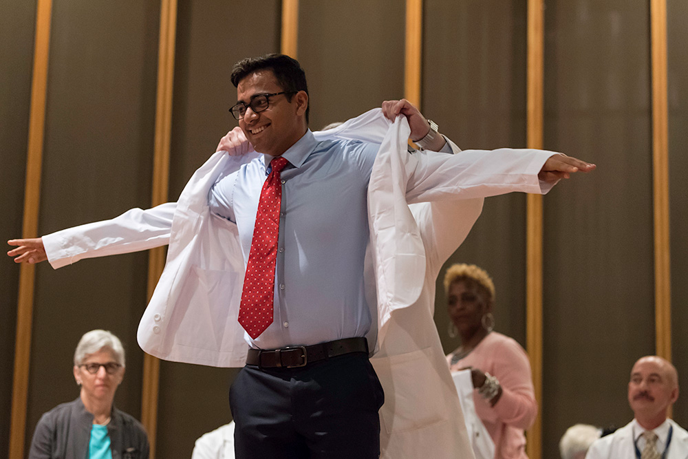 Feature image students puts on a white doctors lab coat