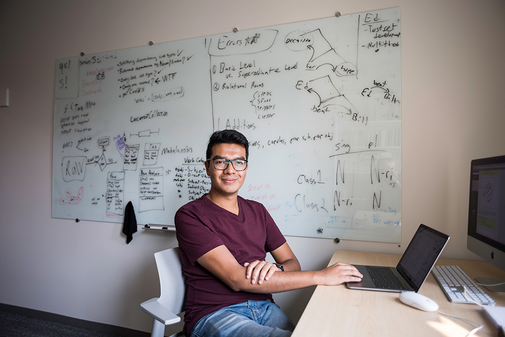 portrait of Aeshaan Wahlang sitting in front of a white board covered in scientific writing