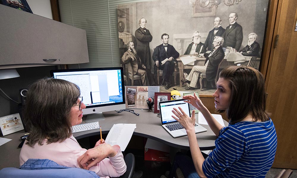 Librarian Margaret Becket and student conferring at desk.