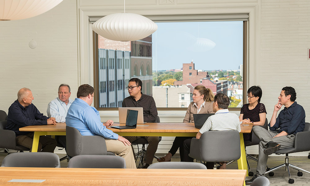 business and science colleagues around a table with the Rochester Data Science Consortium at the Incubator at Sibley Square