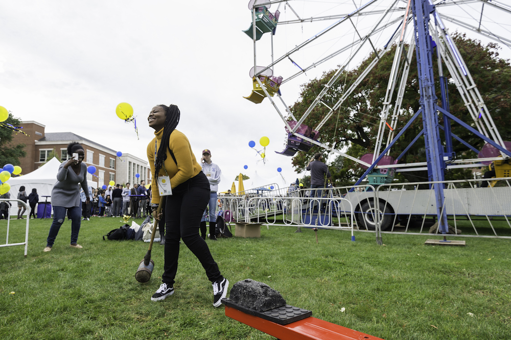 two students laugh while playing a carnival game