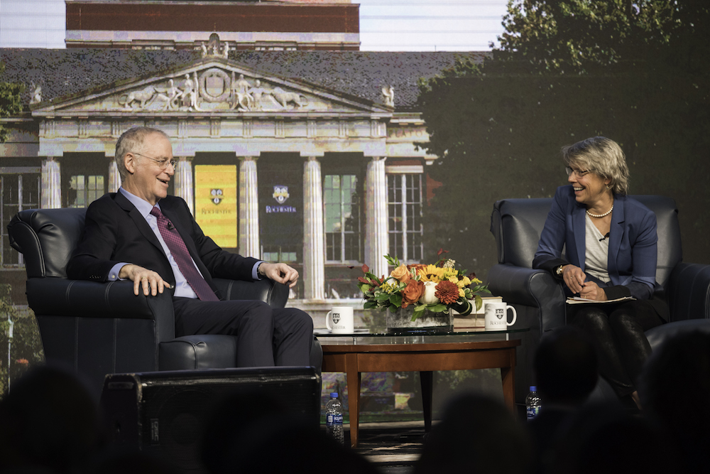 Ron Chernow and Joanna Scott sit in chairs on a stage