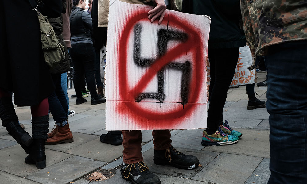 hand holding a crossed-out swastika sign.