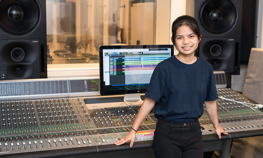 students stands in front of a large sound board