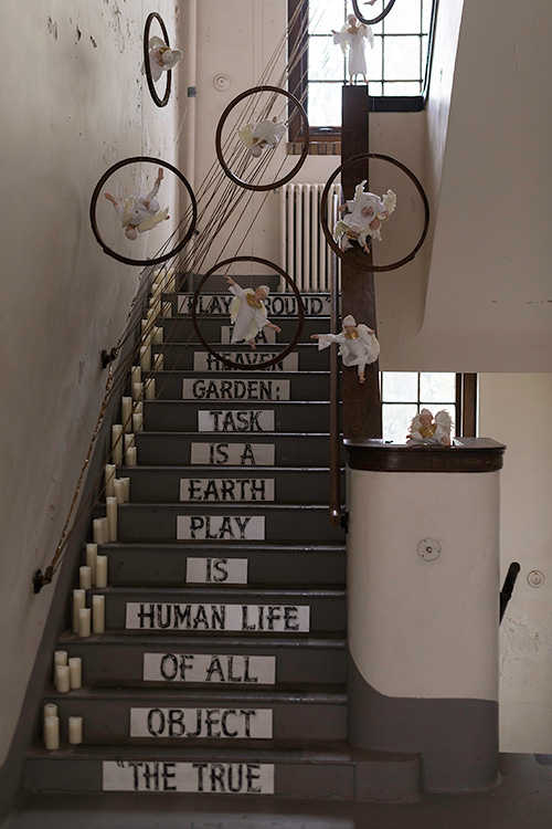 a stair case of an old building, and on each step there is writing so that the whole staircase spells out THE TRUE OBJECT OF HUMAN LIFE IS PLAY. EARTH IS A TASK GARDEN: HEAVEN IS A PLAYGROUND 