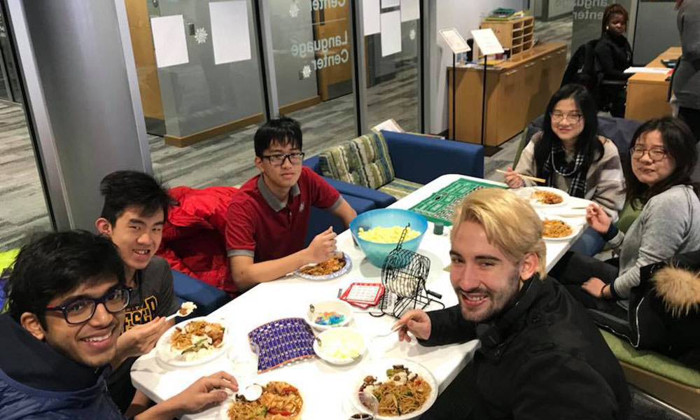 Feature image group of students at a table eating food and playing games