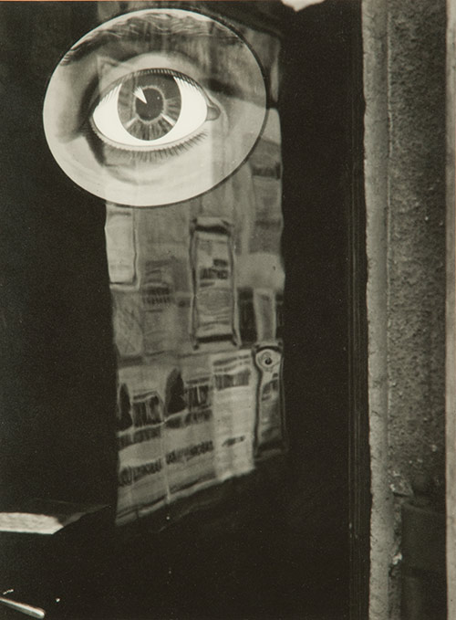 photo of a door covered in newsprint with a large illustration of a human eye.