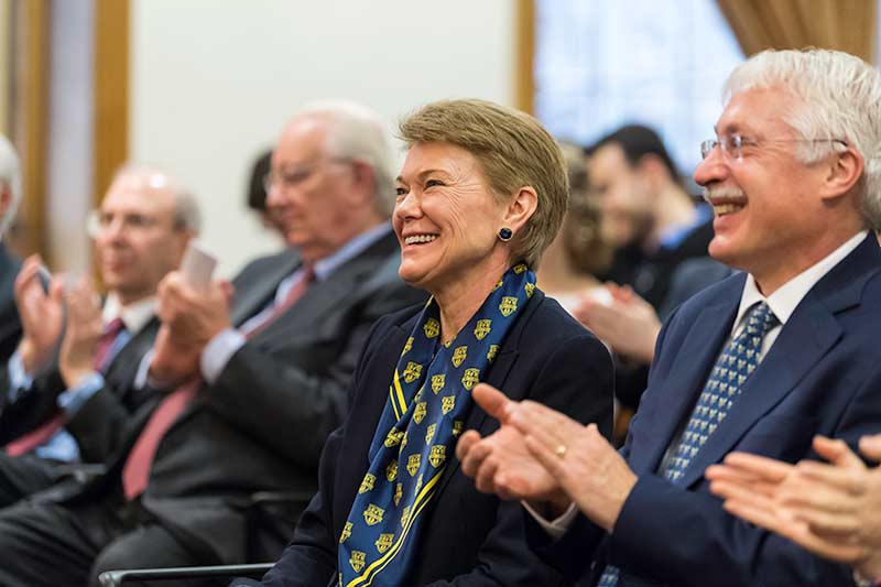 people seated in a row, smiling and applauding.