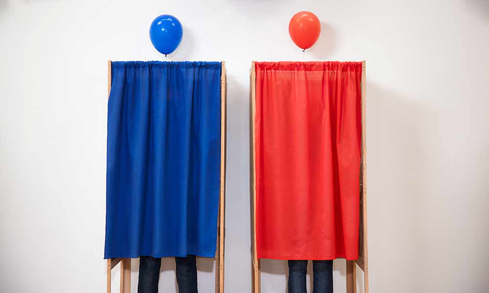 photo of two voting booths side by side, one read and one blue