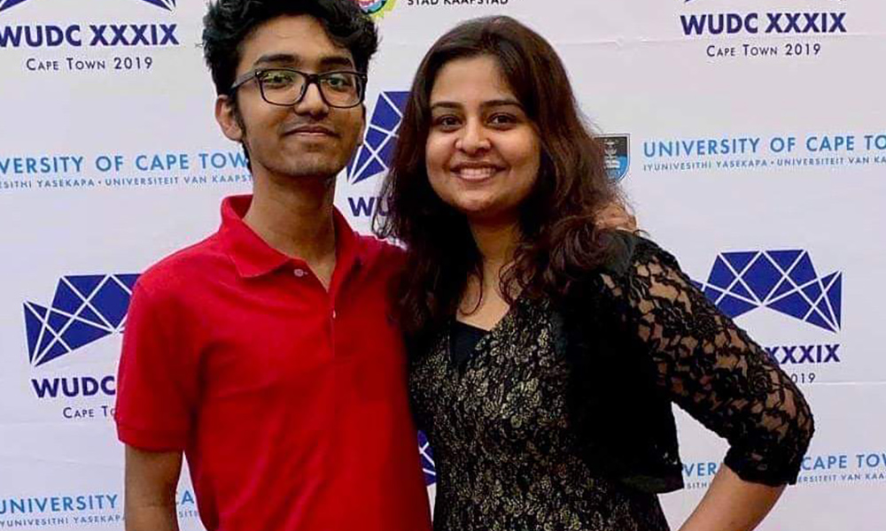 two students pose for a portrait in front of a backdrop with the WUDC Cape Town 2019 logo