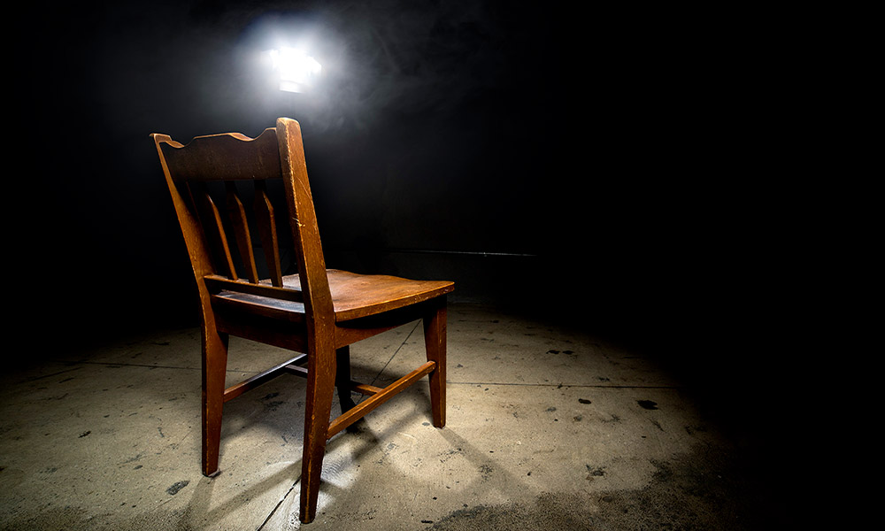 Feature image a chair in an empty room with a light overhead, like in an interrogation room