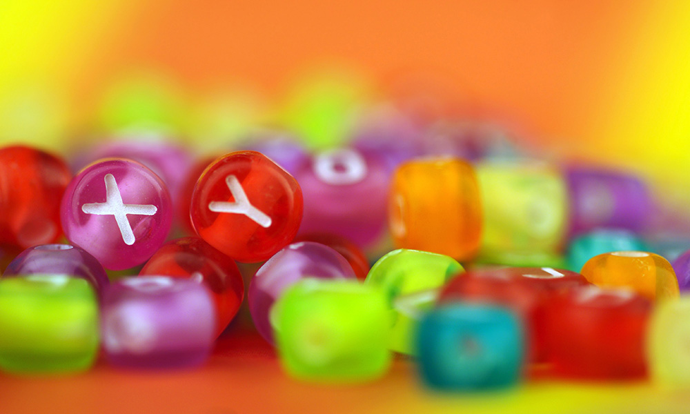 large pile of colorful beads, two of them with the letters X and Y.