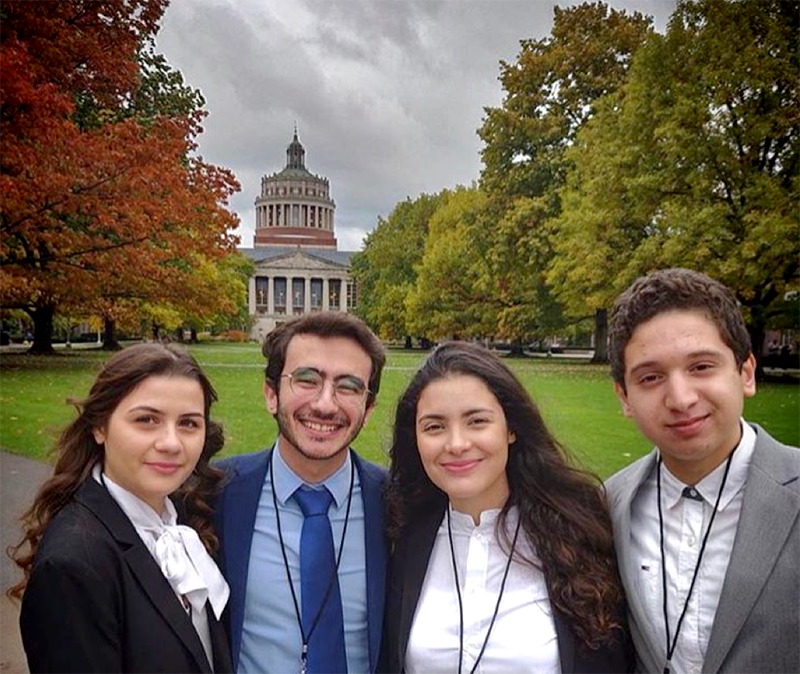 Group of four students posing in front of Rush Rhees Library.