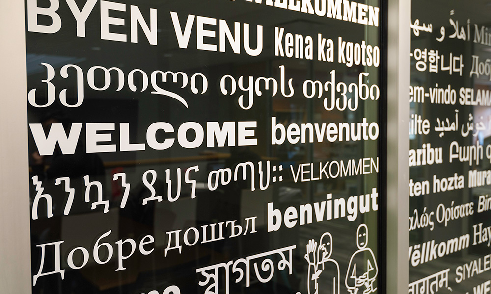 words in multiple languages appear etched on a glass door