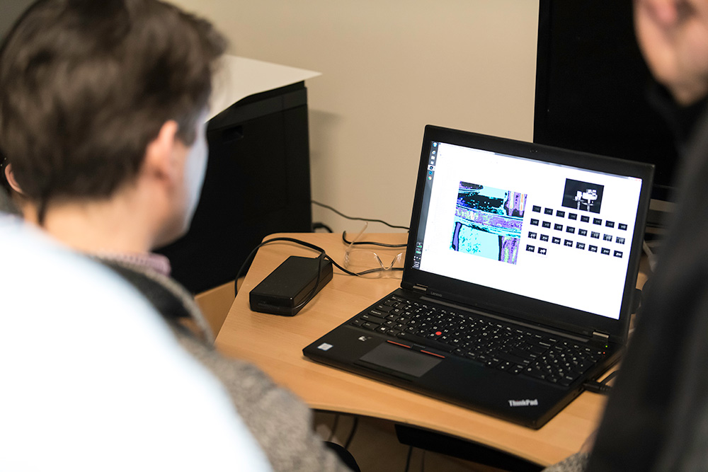 people looking at a laptop screen showing multiple small images of a scroll.