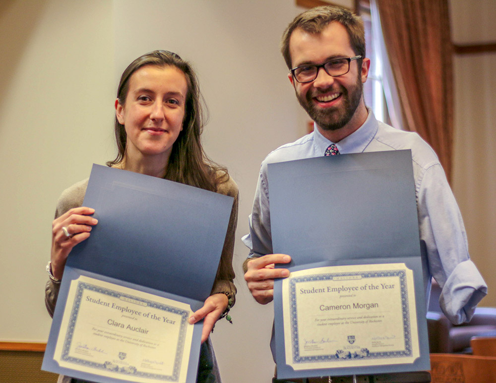 two students holding up certificates of award.