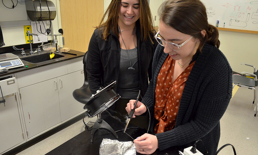 students working with a small manufacturing device