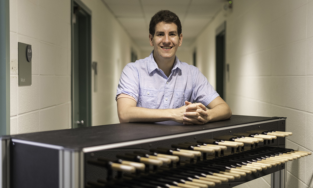 Alex Johnson standing behind a practice carillon