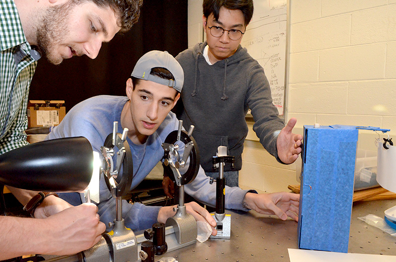 three students working with optics.