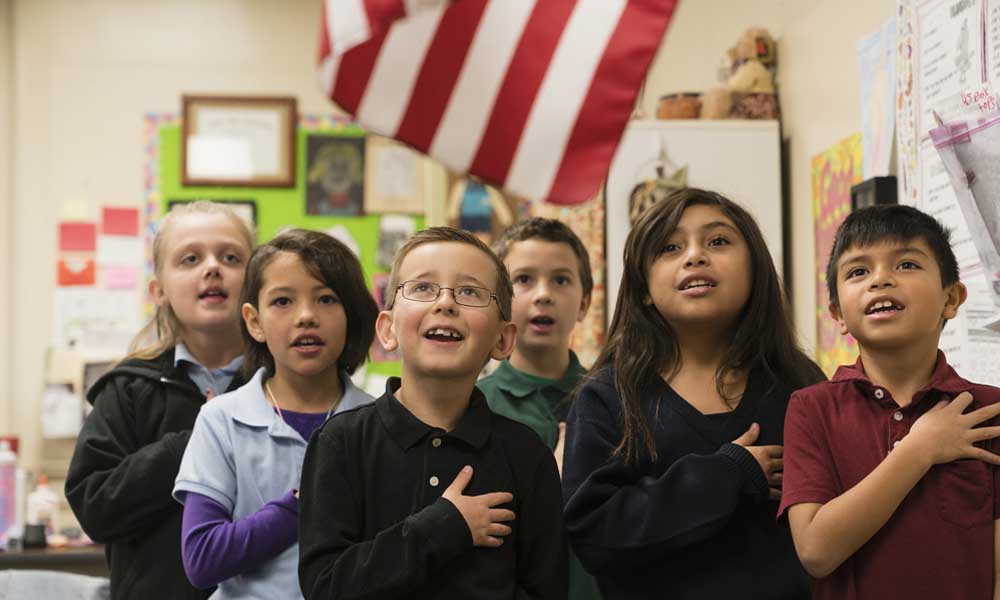 Should patriotism be taught in the classroom? Here, schoolchildren stand for the Pledge of Allegiance.
