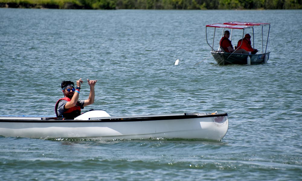 Feature image student pilots a small boat covered in solar panels on a lake during a race